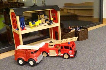 Kleine Feuerwehrautos und Feuerwache aus Holz zum Spielen und Entdecken.