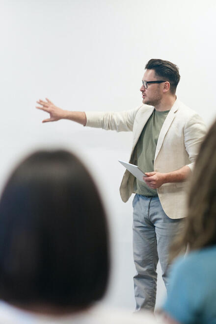 Ein Mann in beigem Blazer unterrichtet.