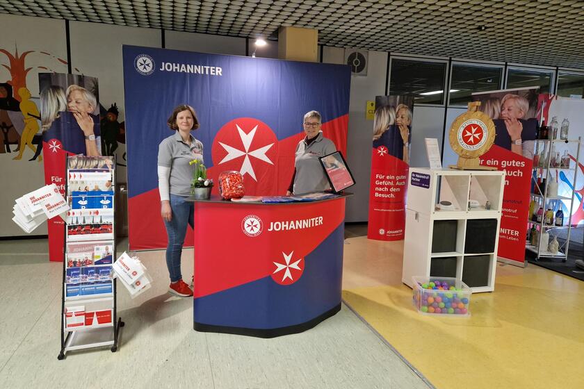 2 Frauen stehen an einem Messestand der Johanniter