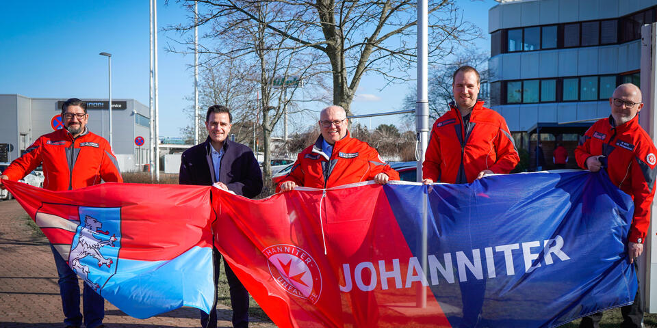 Von links: Michele Sciacca, Bürgermeister Claudio Provenanzo. Ortsbeauftragter Thomas Silbermann, Philipp Petzold (Teamleiter Rettungsdienst) und Michael Merz (Fachbereichsleiter Rettungsdienst) beim Hissen der Flaggen vor der Johanniter-Rettungswache Garbsen.