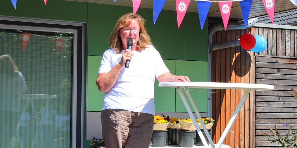 Eine Frau hält ein Mikro und steht an einem Stehtisch