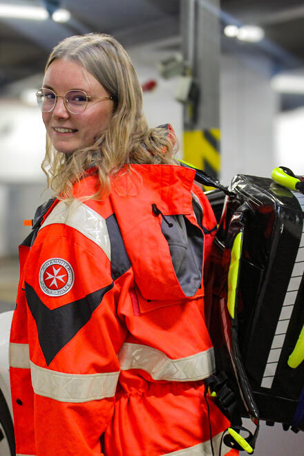 Eine junge Frau mit Johanniter-Bekleidung und einem Rettungsrucksack über der Schulter