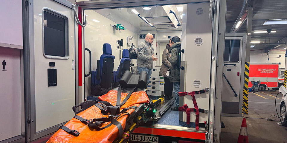 Schülerinnen und Schüle stehen mit einem Mann in Johanniter-Kleidung in einem Rettungswagen.