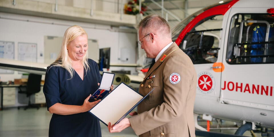 Staatsministerin Stolz zeigt den Orden und Professor Little die Urkunde.