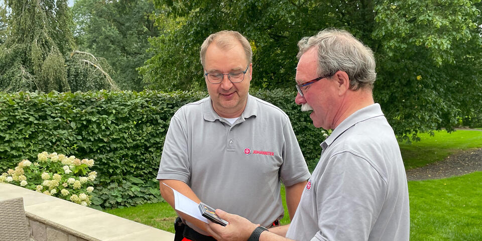 Ein Mann übergibt einem anderen eine Urkunde und eine Medaille