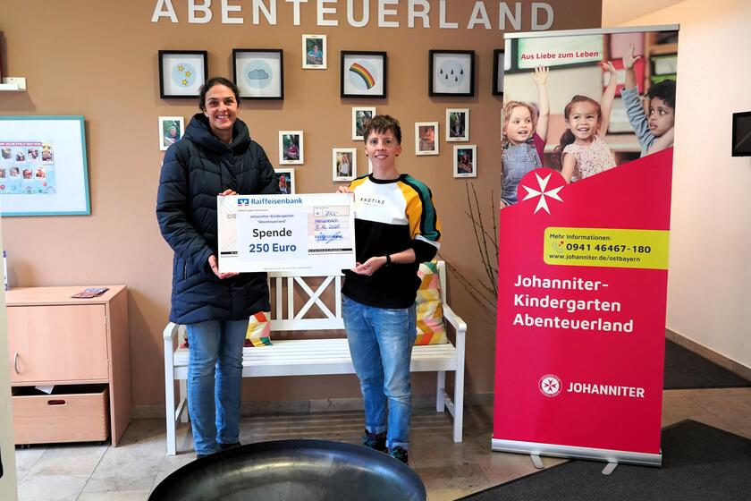 Filialleitung Kathrin Uwe (links) übergibt den symbolischen Spendenscheck an Einrichtungsleitung Daniela Burger (rechts)