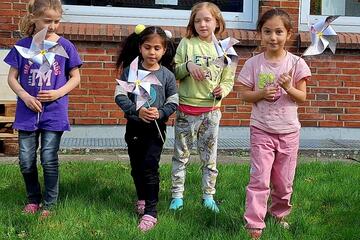 Vier Mädchen zeigen ihre Spielzeug-Windräder
