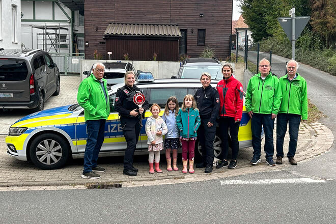 Drei Männer von der Verkehrswacht, zwei Polizistinnen, drei kleine Mädchen und eine Johannitern vor einem Streifenwagen