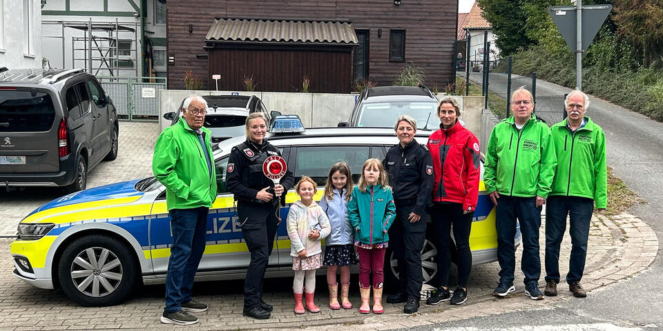 Drei Männer von der Verkehrswacht, zwei Polizistinnen, drei kleine Mädchen und eine Johannitern vor einem Streifenwagen