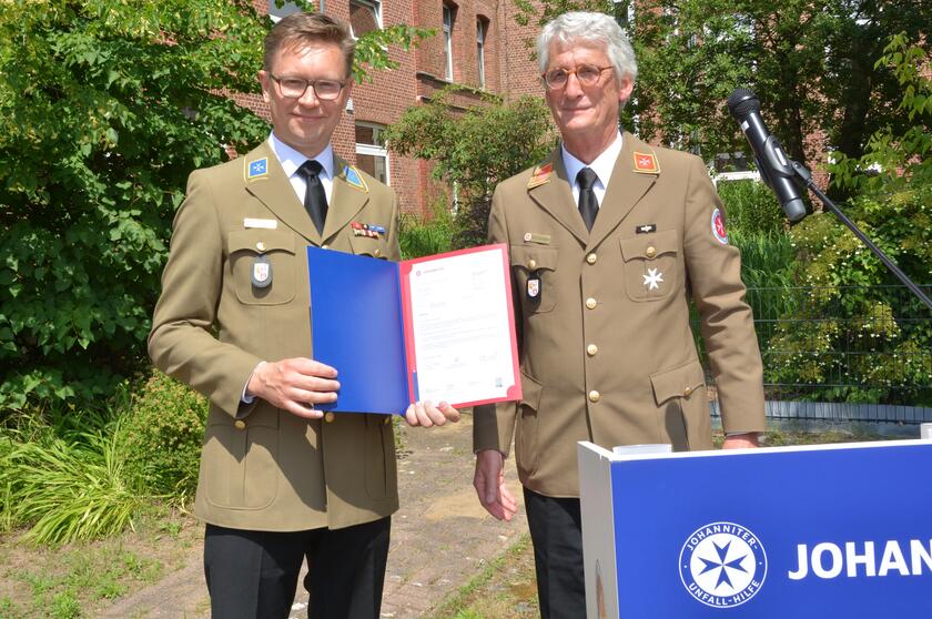 Zwei Männer mit einer Ernennungsurkunde.