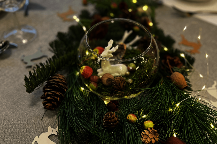 Detail der Tischdekoration mit Tannengrün, Zapfen und weihnachtlichen Elementen