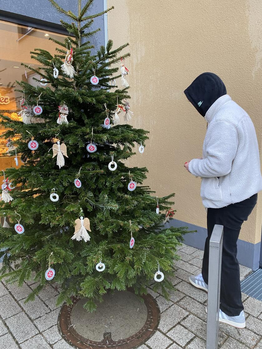 Ein Christbaum wird mit selbstgebasteltem Schmuck aus der Tagespflege Bobingen behangen.