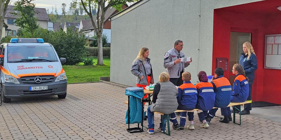 Ein Johanniter erklärt Kindern etwas