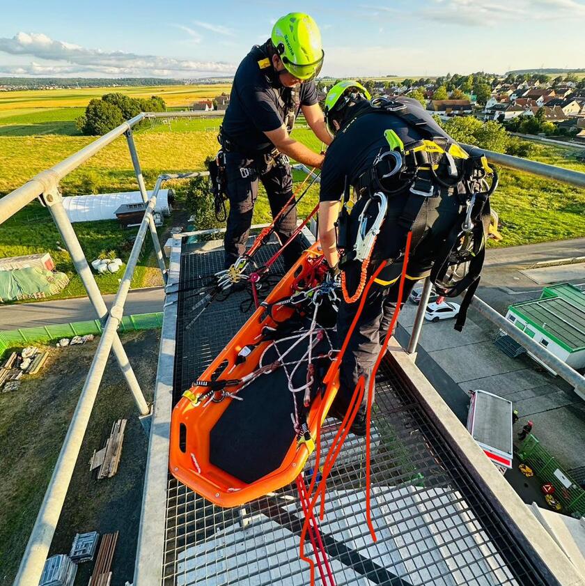 Höhenretter sind in Aktion und befestigen eine Trage um eine Person abzuseilen