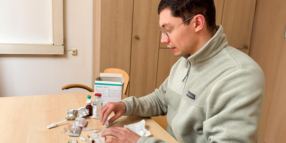 Ein junger Mann sitzt an einem Tisch und arbeitet mit Spritzen