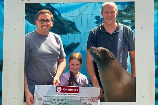 Spendenübergabe ZOO Duisburg- vor dem Bauzaun der Seelöwenanlage von links nach rechts: Christian Schreiner, Referent Sponsoring und Öffentlichkeitsarbeit, Julia Riering, Andreas Riering, Leitung Therapiezentrum