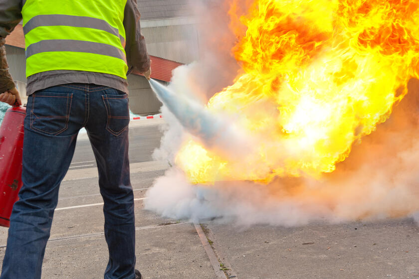 Eine Person löscht mit einem Feuerlöscher ein Feuer