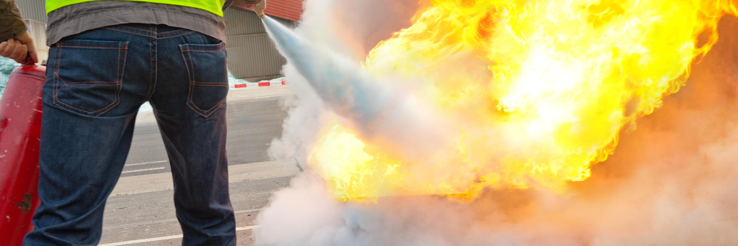 Eine Person löscht mit einem Feuerlöscher ein Feuer