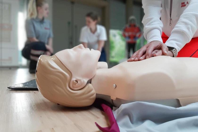 Eine Trainingspuppe an der eine Person Wiederbelebung übt.