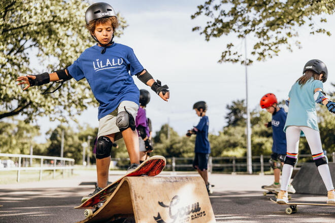Skateboard-Workshop im Freien: Kinder mit Helm üben Tricks beim Lilalu-Ferienprogramm.