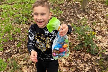 Ein Junge hat im Freien eine Tüte mit Ostereiern gefunden.