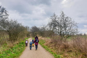 Die Kinder sind mit einer Erzieherin in der angrenzenden Natur unterwegs.