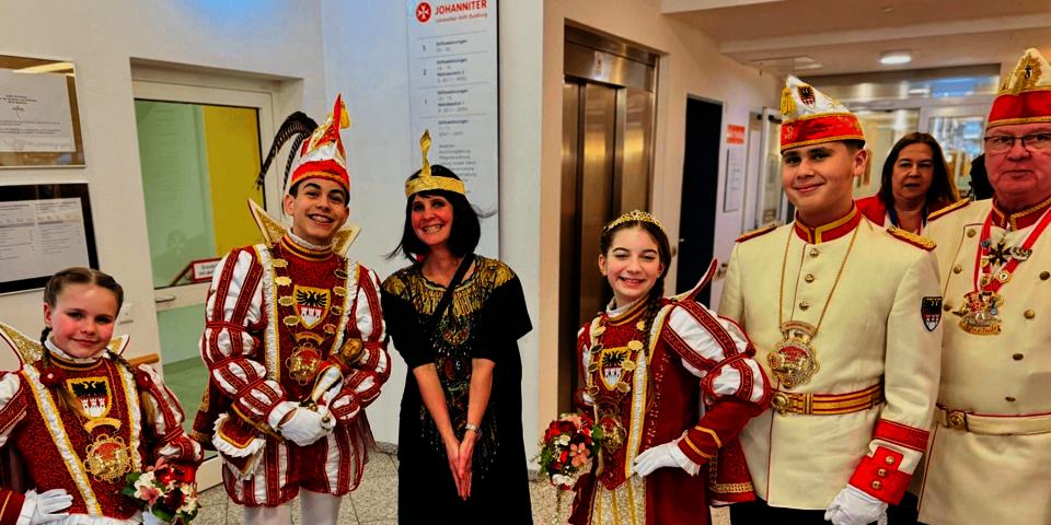 Gruppenfoto mit Kinderprinzen und Begleitung in rot-weißen Kostümen im Flur.