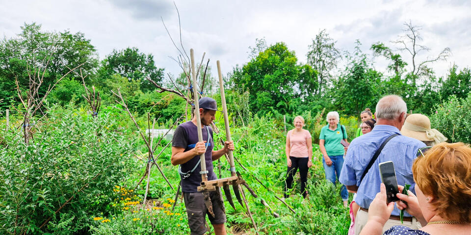 Ein Mann erklärt Personen auf einem Acker etwas