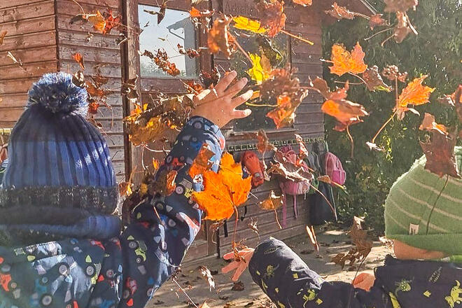 Kinder werfen Herbstlaub hoch