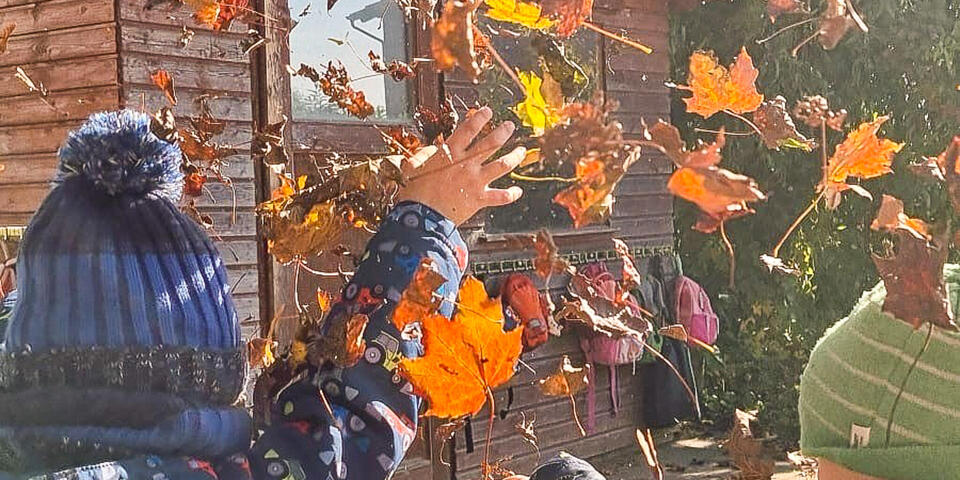 Kinder werfen Herbstlaub hoch