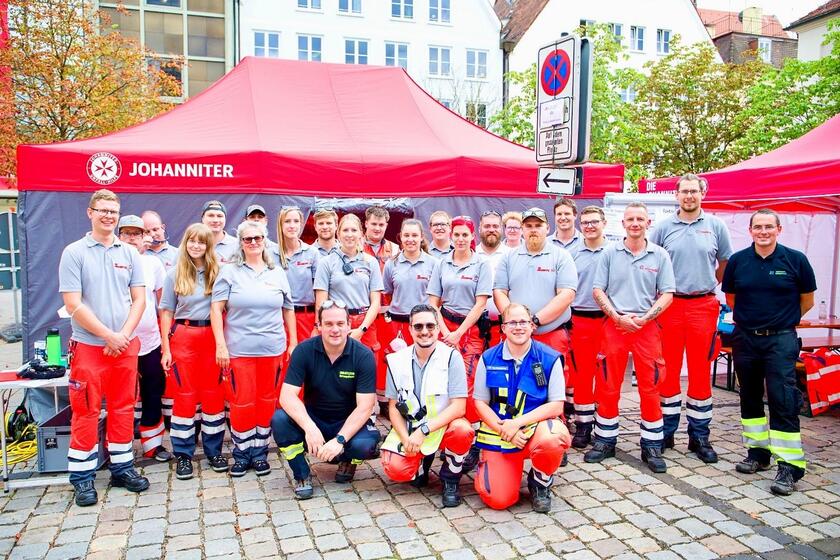 Ein Gruppenfoto der Ehrenamtlichen vor einem Johanniter-Zelt in der Stadt.