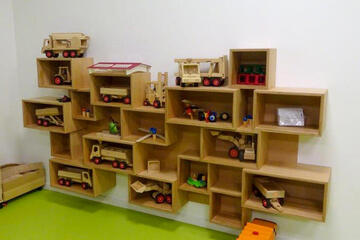 Wandregal mit zahlreichen Spielsachen wie beispielsweise kleine Eisenbahnen, Traktoren und Co.