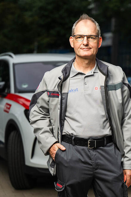 Ein Arzt im ärztlichen Bereitschaftsdienst steht vor einem Fahrzeug und schaut in die Kamera.
