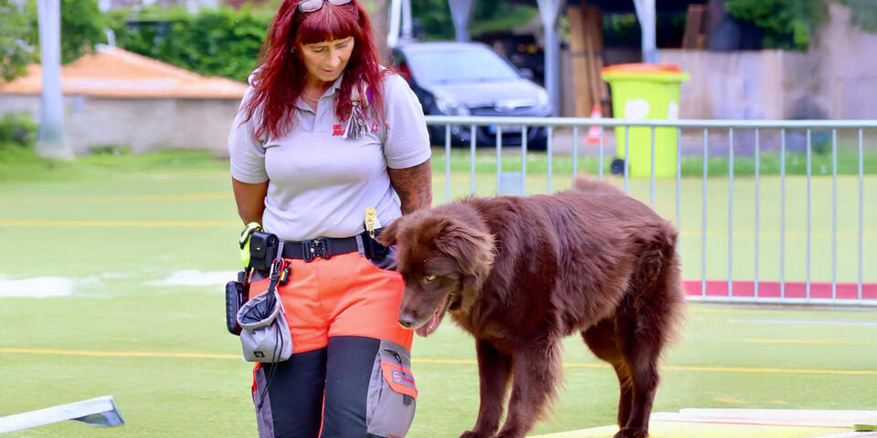 Eine Johanniterin mit Hund, der über einen Balken läuft