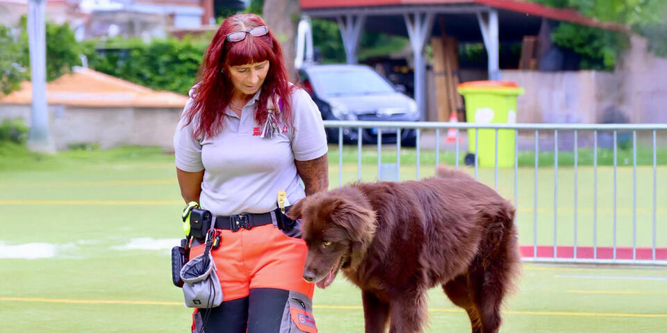 Eine Johanniterin mit Hund, der über einen Balken läuft