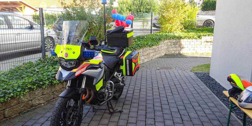 Ein Johanniter-Motorrad neben einem Haus.