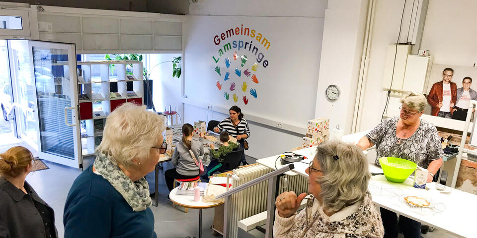 In einem Gemeinschaftsraum stehen Menschen und unterhalten sich