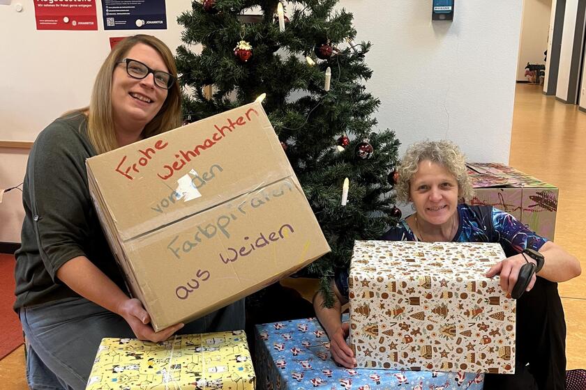 Mitarbeitende halten Päckchen in die Kamera