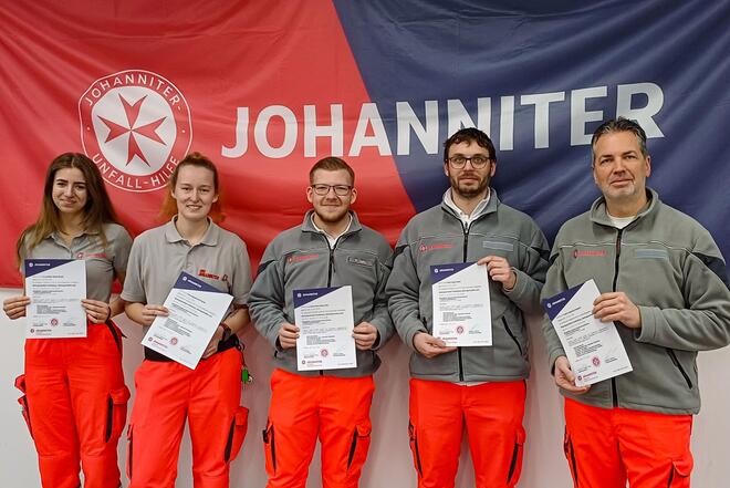 Drei Johanniter und zwei Johanniterinnen mit einer Urkunde