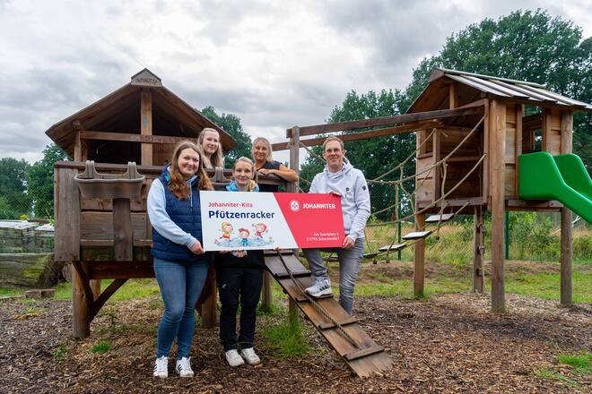 Das Team rund um Nils Kühn (r.) freut sich nicht nur über den neuen Namen der Johanniter-Kita Schackendorf, sondern auch über das neue Schild, das künftig die Kinder bei den Pfützenrackern willkommen heißen wird.