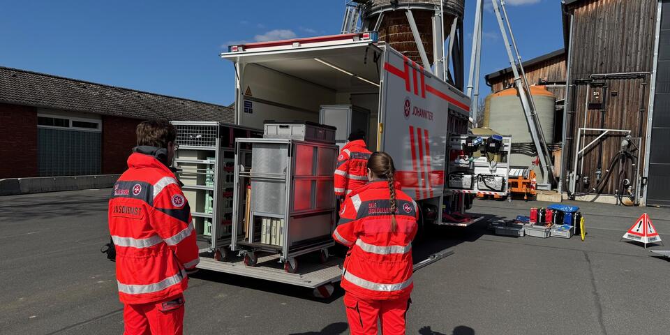 Johanniter vor einem offenen Gerätewagen