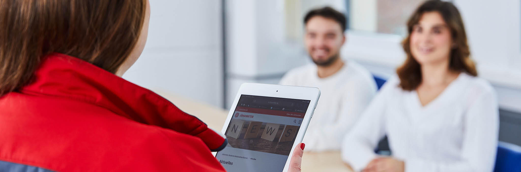 Eine Ausbilderin in der Pflegeschule erklärt den Auszubildenden etwas mithilfe eines Tablets.