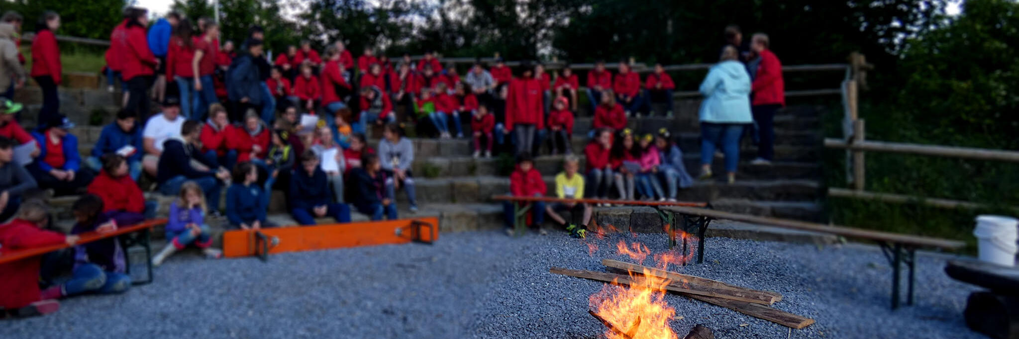 Johanniter-Jugendliche sitzen um ein Lagerfeuer