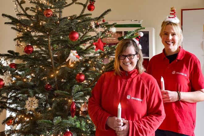 Die Tagespflegeleitung und eine Betreuungskraft stehen vor dem geschmückten Weihnachtsbaum
