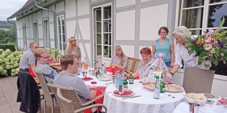 Menschen sitzen auf einer Terasse gemütlich zusammen