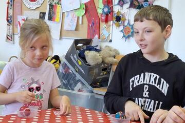 Ostervorbereitung: Ein Mädchen und ein Junge sitzen am Tisch und schmücken Ostereier.