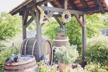 Eine Weinpresse und ein Weinfass im Garten