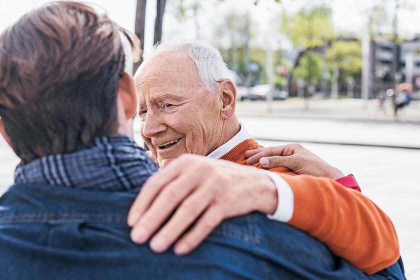 Ein älterer Mann umarmt einen anderen Mann