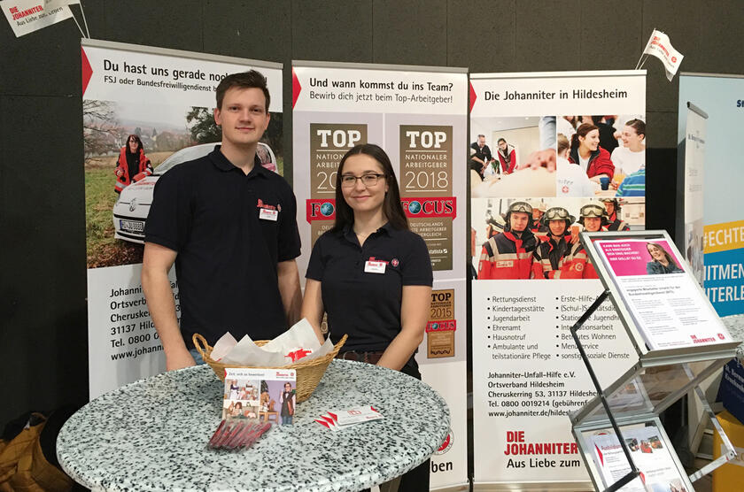 Ein junger Mann und eine junge Frau stehen an einem Messestand