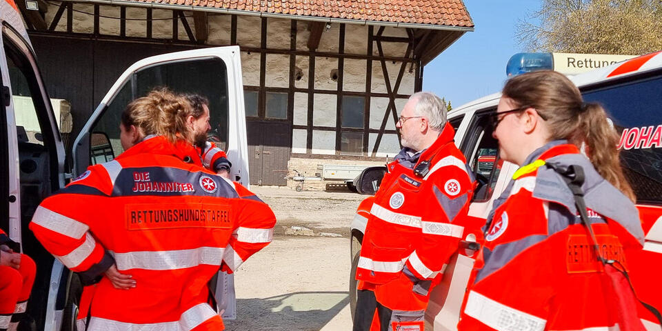 Johanniter-Einsatzkräfte der Rettungshundestaffel an Johanniter-Fahrzeugen